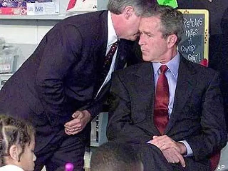 Zu-diesem-Zeitpunkt-in-einer-Grundschule-in-Florida-Ein-Mitarbeiter-informiert-Praesident-Bush-ueber-die-beiden-Anschlaege-in-New-York-Wie-im-Schock-bleibt-Bush-sitzen
