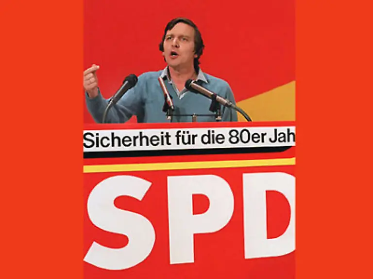 1980-wird-Schroeder-in-den-Deutschen-Bundestag-gewaehlt-Seine-Jungfernrede-haelt-er-in-der-Debatte-ueber-Jugendprotest-im-demokratischen-Staat-147-Als-erster-Abgeordneter-in-der-Geschichte-des-Bundestages-tritt-er-dabei-ohne-Krawatte-ans-Pult