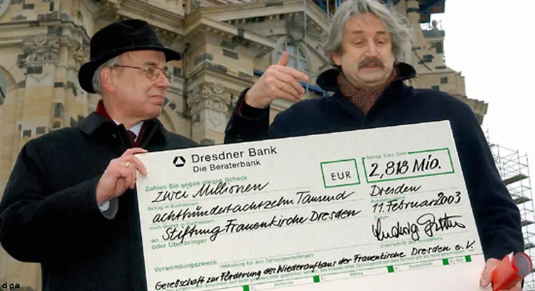 Eine-beispiellose-Sammlungsbewegung-rollte-an-2003-konnte-der-Trompeter-Ludwig-Guettler-r-einen-Spendenscheck-ueber-2-818-Mio-Euro-an-Landesbischof-Volker-Kress-ueberreichen-Mehr-als-zwei-Drittel-der-Bausumme-stammen-aus-privaten-Spenden-oder-Erloesen