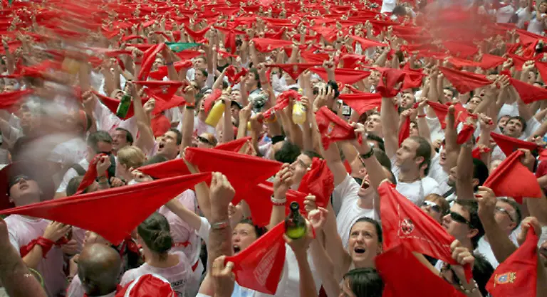 Junge-Maenner-mozos-die-weisse-Hosen-und-Hemden-sowie-rote-Halstuecher-und-Schaerpen-tragen-laufen-bei-der-Jagd-vor-den-Tieren-her