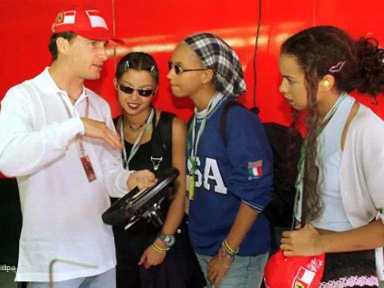 Trotzdem-mussten-sie-sich-immer-wieder-aergern-zum-Beispiel-ueber-besserwisserische-Machos-Der-britische-Formel-1-Pilot-Eddie-Irvine-erklaert-den-interessierten-Saengerinnen-in-der-Ferrari-Box-die-Funktion-eines-Auto-Lenkrads