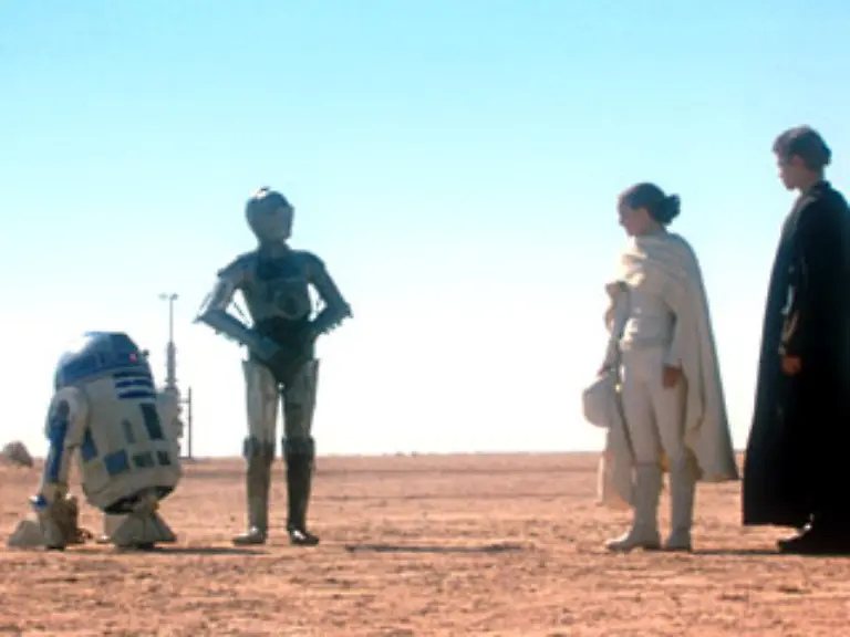 Anakin-findet-seine-Mutter-in-einem-Lager-der-Sandleute-gefesselt-und-sterbend-Blinder-Hass-treibt-ihn-zu-einem-Massaker-an-den-Sandleuten-ihren-Frauen-und-Kindern-Mit-dem-Leichnam-seiner-Mutter-kehrt-er-zu-ihrem-Ehemann-Lars-zurueck-Der-Droide-R2-D2-wartet-derweil-im-Raumschiff-und-empfaengt-einen-Notruf-von-Kenobi