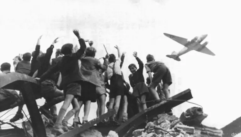 Als-Reaktion-auf-die-Waehrungsreform-in-den-Westzonen-und-im-westlichen-Sektor-Berlins-kommt-es-zur-Berlin-Blockade-vom-24-Juni-1948-bis-zum-12-Mai-1949-durch-die-Sowjetunion-Die-Bevoelkerung-wird-durch-Rosinenbomber-ueber-die-Berliner-Luftbruecke-versorgt