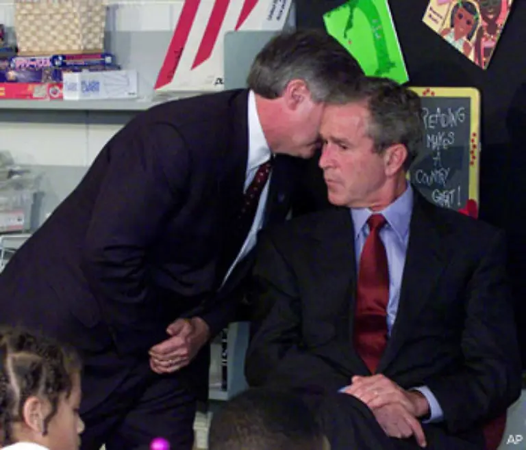 Zu-diesem-Zeitpunkt-in-einer-Grundschule-in-Florida-Ein-Mitarbeiter-informiert-Praesident-Bush-ueber-die-beiden-Anschlaege-in-New-York-Wie-im-Schock-bleibt-Bush-sitzen