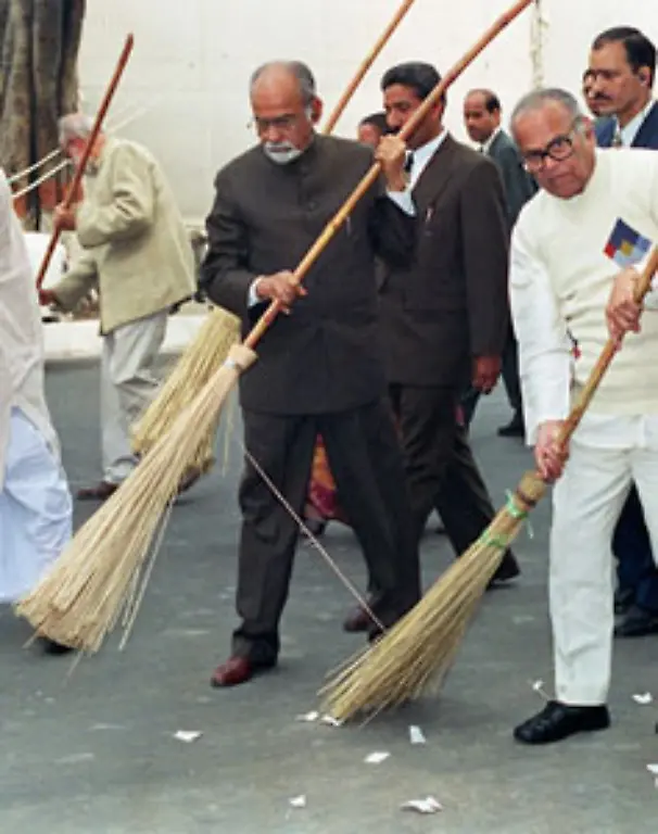 Alle-Bewohner-des-Ashrams-muessen-auch-niedere-Taetigkeiten-erledigen-Der-damalige-indische-Premier-Inder-Kumar-Gujral-bei-einer-symbolischen-Strassenreinigung-1998-in-Erinnerung-an-Gandhi