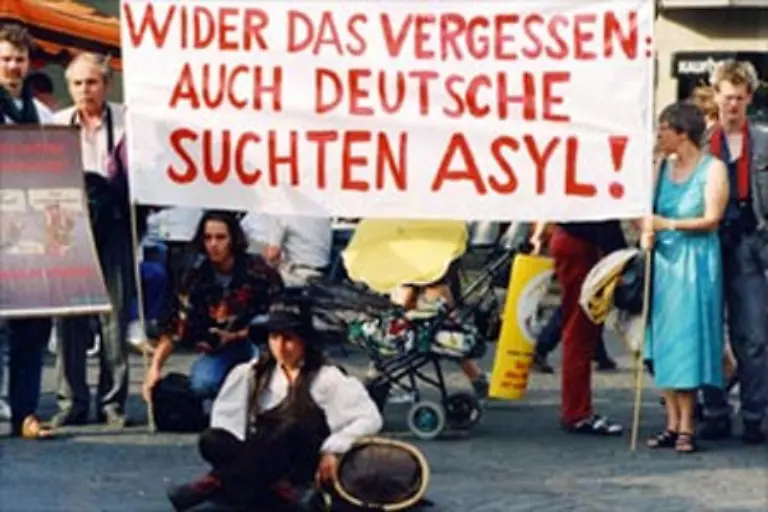 Auf-der-politischen-Buehne-erhitzt-Anfang-der-90er-Jahre-die-Asyl-Debatte-die-Gemueter-Schily-gehoert-zu-denjenigen-die-sich-fuer-eine-Einschraenkung-des-Asyl-Rechts-stark-machen-in-Konfrontation-zu-seinen-ehemaligen-gruenen-Mitstreitern-und-der-SPD-Linken