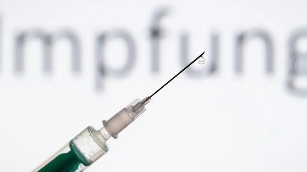 Eine-Spritze-wird-vor-den-Schriftzug-Impfung-gehalten