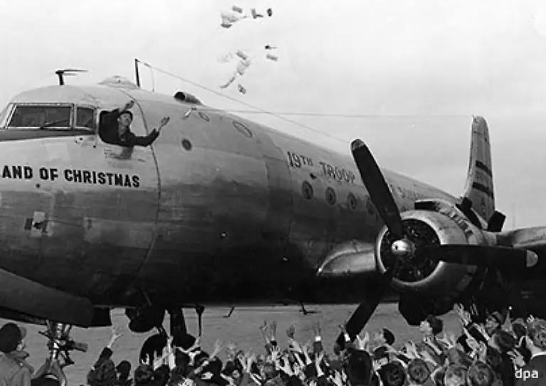 Zur-Freude-der-Kinder-in-der-Nachbarschaft-des-Flughafens-warf-der-amerikanische-Pilot-Gail-Halvorsen-beim-Anflug-auf-Tempelhof-Suessigkeiten-an-Fallschirmen-aus-Taschentuechern-ab