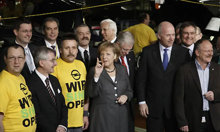 Gruppenbild-mit-Kanzlerin-Im-schwarzen-Tuch-vorn-links-Opel-Chef-Hans-Demant-Angela-Merkel-in-grau-und-Carl-Peter-Forster-rechts-mit-blauer-Krawatte-Betriebsratschef-Klaus-Franz-ganz-rechts-traegt-sein-Hemd-offen