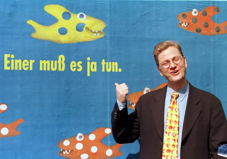 Guido-Westerwelle-party-manger-of-Germany-s-Free-Democratic-Party-poses-for-photographers-in-front-of-a-campaign-poster-in-Bonn-June-13-The-poster-reads-someone-has-to-do-it-and-shows-a-fish-swimming-against-the-current