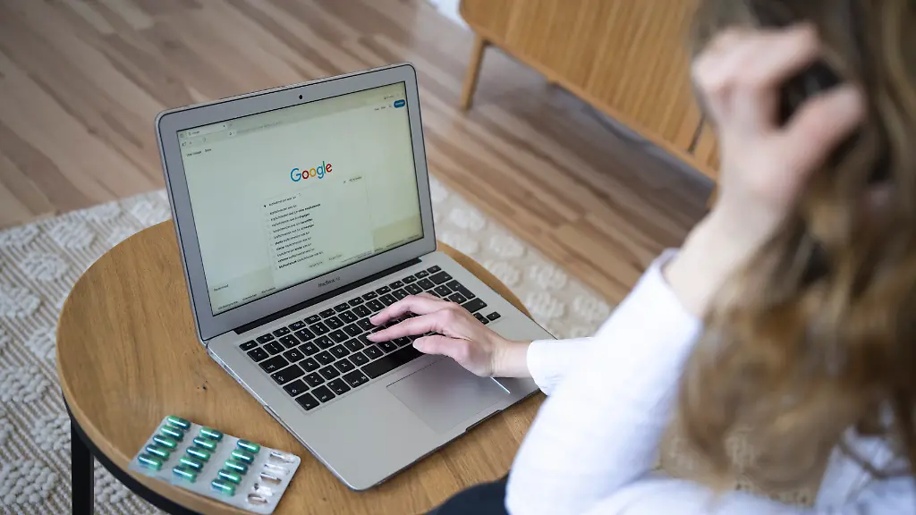 Eine-Person-gibt-in-die-Google-Suche-Kopfschmerzen-was-tun-ein-daneben-liegen-Tabletten-in-einer-Blisterpackung-Viele-Menschen-informieren-sich-online-zu-gesundheitlichen-Beschwerden-was-neben-Informationen-auch-Verunsicherung-ausloesen-kann