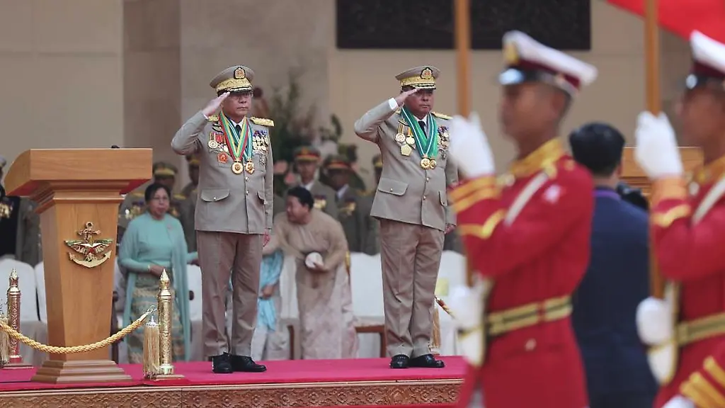 In-this-photo-provided-by-Myanmar-Military-True-News-Information-Team-Myanmar-military-leader-Senior-Gen-Min-Aung-Hlaing-left-on-the-stage-salute-together-with-newly-appointed-commander-in-chief-Gen-Ye-Win-Oo-right-on-the-stage-to-guard-of-honor-during-a-ceremony-Monday-March-30-2026-in-Naypyitaw-Myanmar
