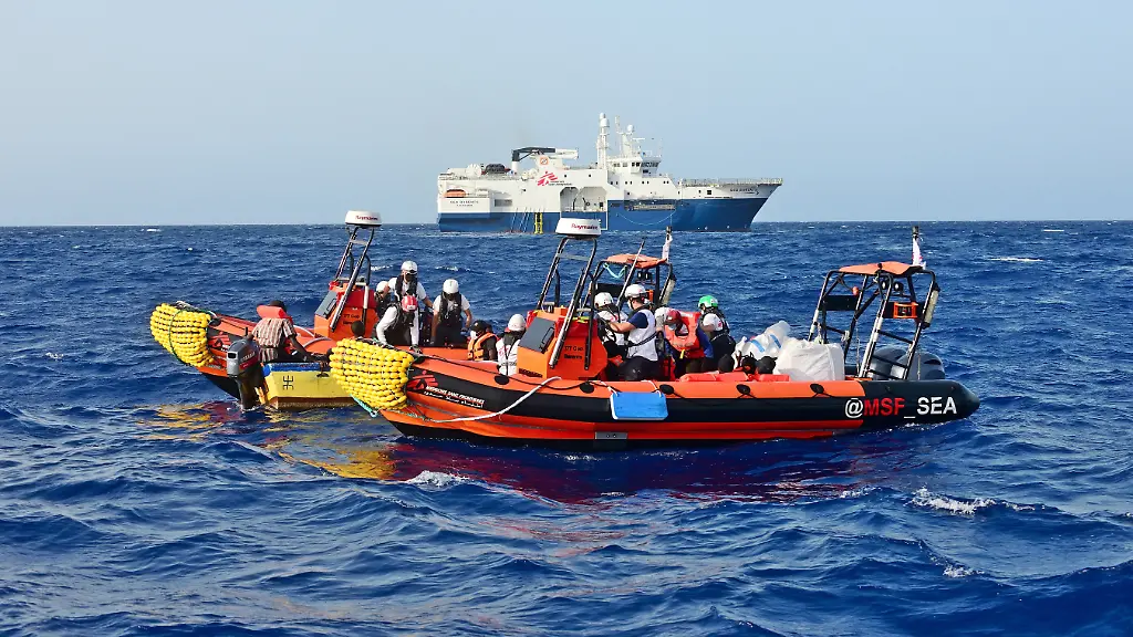 Seenotrettung-im-zentralen-Mittelmeer-Viele-Menschen-fluechten-von-Libyen-aus-ueber-das-Mittelmeer-nach-Lampedusa-und-Malta-Viele-verungluecken-toedlich-zahlreiche-Menschen-werden-zurueck-nach-Libyen-gebracht-Private-Seenotretter-sind-so-oft-wie-moeglich-vor-Ort-um-den-Menschen-in-Seenot-zu-helfen-Im-Bild-Retter-auf-einem-Beiboot-der-Geo-Barents-von-Aerzte-ohne-Grenzen-Hintergrund-bei-einer-Rettung