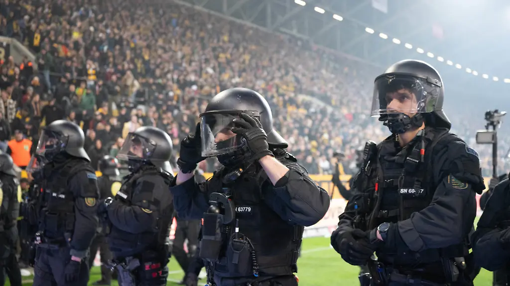 04-04-2026-Sachsen-Dresden-Fussball-Maenner-2-Bundesliga-Dynamo-Dresden-Hertha-BSC-28-Spieltag-im-Rudolf-Harbig-Stadion-Polizisten-stehen-waehrend-einer-Spielunterbrechung-im-Stadion-vor-dem-Gaesteblock-Foto-Sebastian-Kahnert-dpa-WICHTIGER-HINWEIS-Gemaess-den-Vorgaben-der-DFL-Deutsche-Fussball-Liga-bzw-des-DFB-Deutscher-Fussball-Bund-ist-es-untersagt-in-dem-Stadion-und-oder-vom-Spiel-angefertigte-Fotoaufnahmen-in-Form-von-Sequenzbildern-und-oder-videoaehnlichen-Fotostrecken-zu-verwerten-bzw-verwerten-zu-lassen