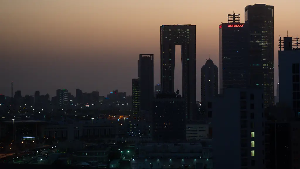 Die-aufgehende-Sonne-faerbt-den-Himmel-hinter-der-Skyline-von-Kuwait-City-roetlich