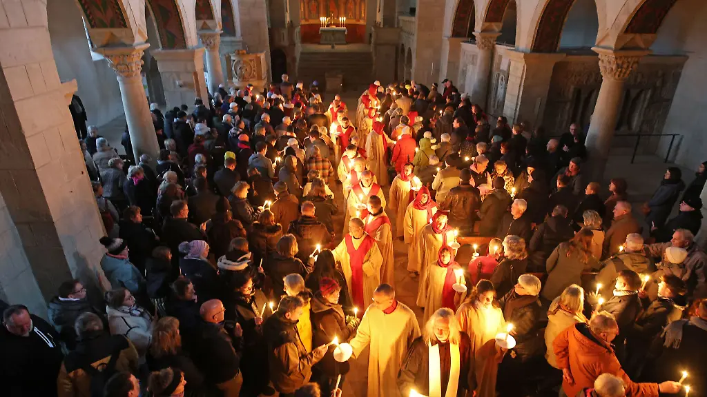 Glaeubige-verteilen-das-Osterlicht-in-der-Stiftskirche-St-Cyriakus