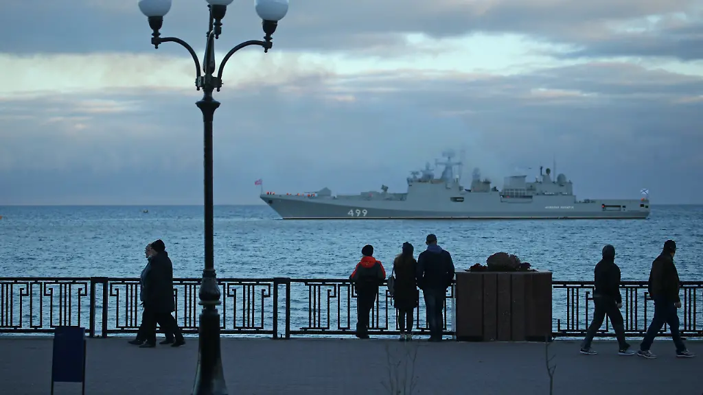 FEODOSIA-RUSSIA-NOVEMBER-28-2020-People-walk-by-the-Black-Sea-Pictured-in-the-background-is-the-Russian-frigate-Admiral-Makarov