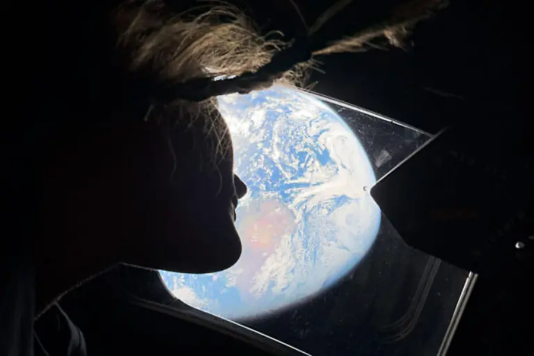 NASA-astronaut-and-Artemis-II-mission-specialist-Christina-Koch-peers-out-of-one-of-the-Orion-spacecraft-s-main-cabin-windows-looking-back-at-Earth-as-the-crew-travels-towards-the-Moon-NASA-astronauts-Commander-Reid-Wiseman-Pilot-Victor-Glover-and-Mission-Specialist-Koch-and-CSA-Canadian-Space-Agency-astronaut-Mission-Specialist-Jeremy-Hansen-launched-at-6-35-p-m-EDT-on-Wednesday-April-1-2026-on-an-approximately-10-day-mission-around-the-Moon-and-back-to-Earth