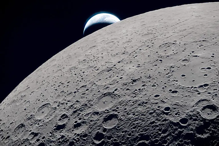 Dieses-von-der-NASA-zur-Verfuegung-gestellte-Bild-zeigt-die-Mondoberflaeche-waehrend-der-Umrundung-auf-der-Artemis-2-Mondmisson-von-der-Orion-Kapsel-aus-Im-Hintergrund-die-Erde-Mit-der-Mission-der-US-Raumfahrtbehoerde-Nasa-fliegen-erstmals-seit-mehr-als-50-Jahren-wieder-Menschen-in-die-Naehe-des-Mondes