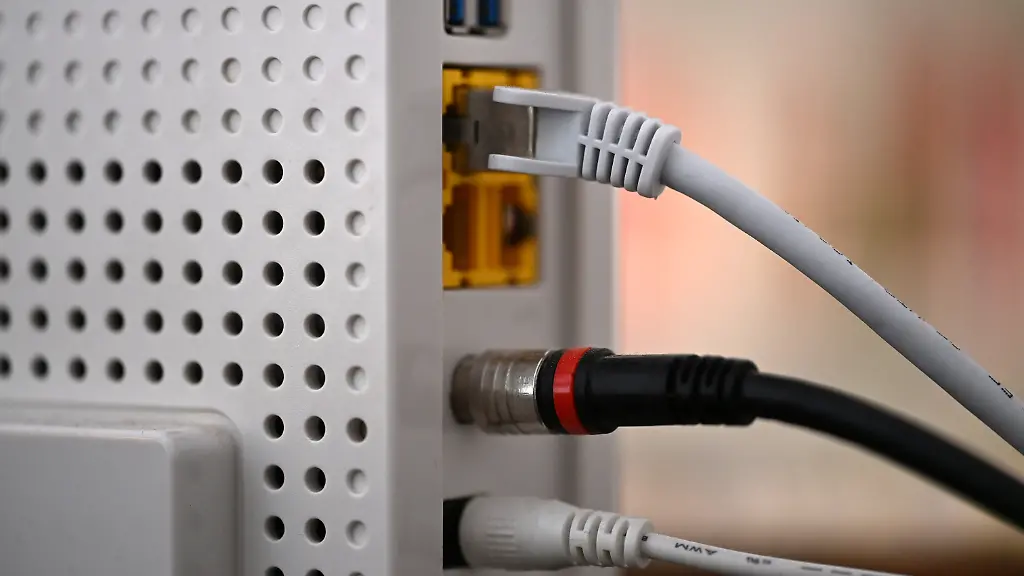 Ein-Router-steht-auf-einem-Schrank-in-einer-Wohnung-zu-sehen-ist-unter-anderem-ein-LAN-Kabel-oben-Laut-Messungen-des-Messtools-breitbandmessung-de-bekommen-Deutschlands-Verbraucherinnen-und-Verbraucher-inzwischen-besseres-Festnetz-Internet