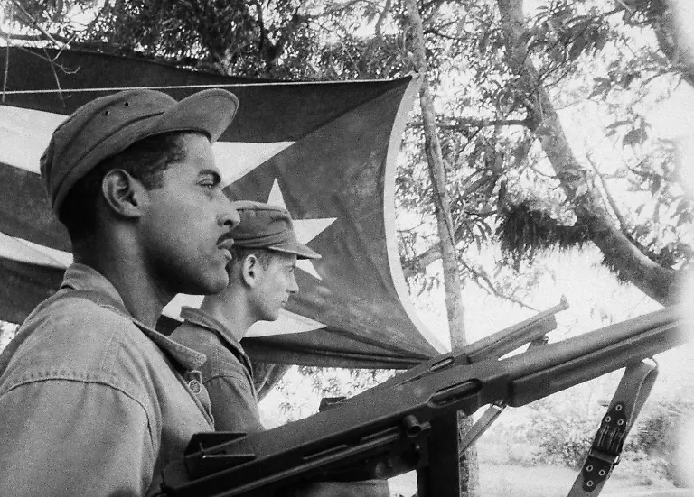 With-a-Cuban-flag-in-the-background-two-Cuban-refugees-train-for-the-invasion-of-the-island-at-a-secret-base-somewhere-in-the-Caribbean-area-April-5-1963-which-was-to-end-in-disaster