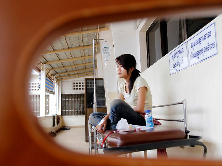 Turnschuhe für westliche Füße: In einem Krankenhaus in Phnom Penh wartet diese Näherin am Tropf hängend auf ihre Entlassung.