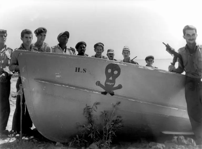 Castro-Soldaten-halten-nach-dem-gescheiterten-Invasionsversuch-in-einer-Bucht-der-Las-Villas-Provinz-neben-einem-der-erbeuteten-Landungsboote-Wache-Eine-vom-US-amerikanischen-Geheimdienst-geplante-und-unterstuetzte-Invasion-Kubas-ist-gescheitert-Castrofeindliche-Exilkubaner-landeten-am-17-04-1961-in-der-Schweinebucht-mit-dem-Ziel-eine-Konter-Revolution-auf-Kuba-zu-entfachen-und-die-sozialistische-Regierung-Fidel-Castros-zu-stuerzen-Die-Invasion-wurde-von-Castros-Soldaten-erfolgreich-verhindert