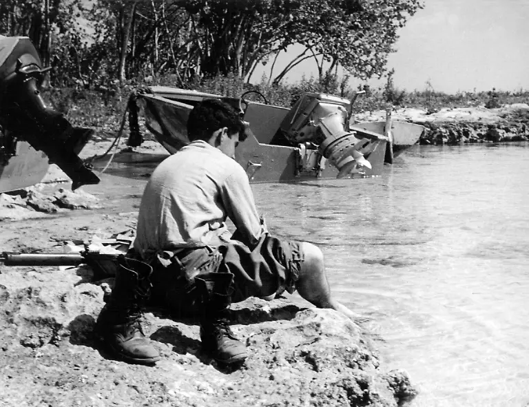 Neben-zerstoerten-Landungsbooten-der-Invasionstruppen-kuehlt-sich-ein-siegreicher-Castro-Soldat-die-Fuesse-im-Wasser-Eine-vom-US-amerikanischen-Geheimdienst-geplante-und-unterstuetzte-Invasion-Kubas-ist-gescheitert-Castrofeindliche-Exilkubaner-landeten-am-17-04-1961-in-der-Schweinebucht-mit-dem-Ziel-eine-Konter-Revolution-auf-Kuba-zu-entfachen-und-die-sozialistische-Regierung-Fidel-Castros-zu-stuerzen-Die-Invasion-wurde-von-Castros-Soldaten-erfolgreich-verhindert