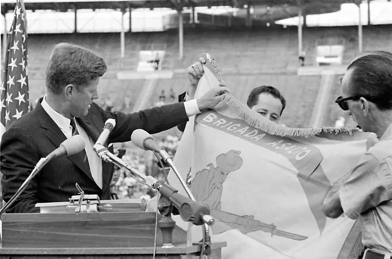 U-S-President-John-F-Kennedy-left-receives-the-combat-flag-of-the-2506-Cuban-invasion-brigade-in-ceremonies-held-at-the-Orange-Bowl-Stadium-in-Miami-Fla-Dec-29-1962