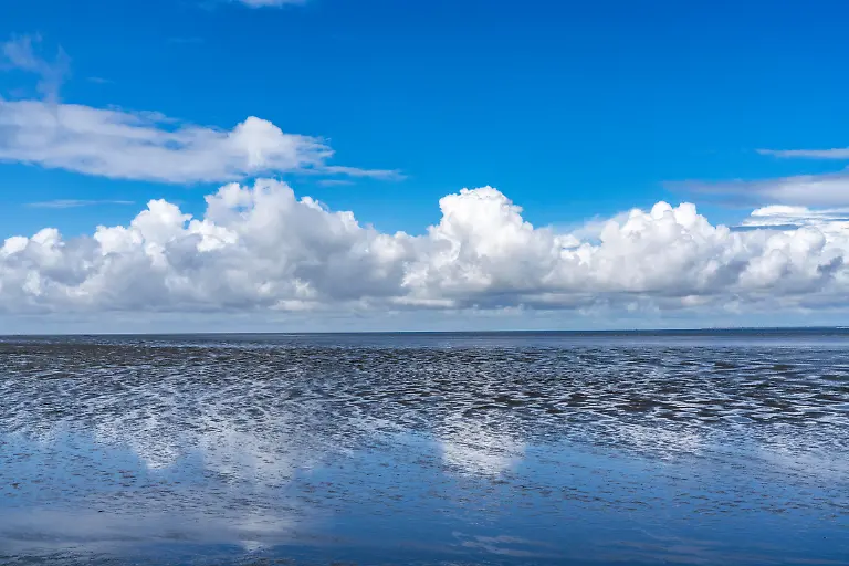 Wattenmeer-zwischen-der-niederlaendischen-Kueste-bei-Eemshaven-und-der-deutschen-Nordseeinsel-Borkum-Nationalpark-Wattenmeer-UNESCO-Weltnaturerbe-Ebbe-Niedrigwasser-Wolken