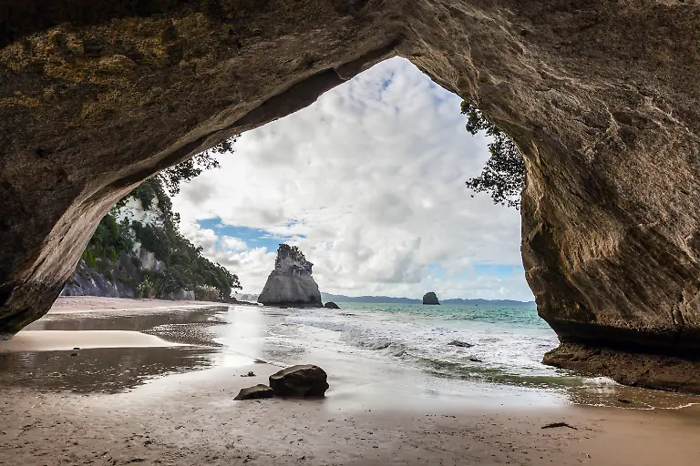 Ocean-tide-in-the-Cathedral-Cave-Mirror-reflections-of-clouds-in-wet-sand-Travel-to-New-Zealand