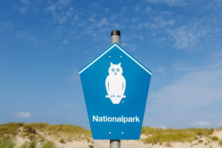 Ein-Schild-mit-einer-Eule-und-dem-Schriftzug-Nationalpark-ist-am-09-08-2025-am-Strand-der-Ostfriesischen-Insel-Norderney-Niedersachsen-zu-sehen