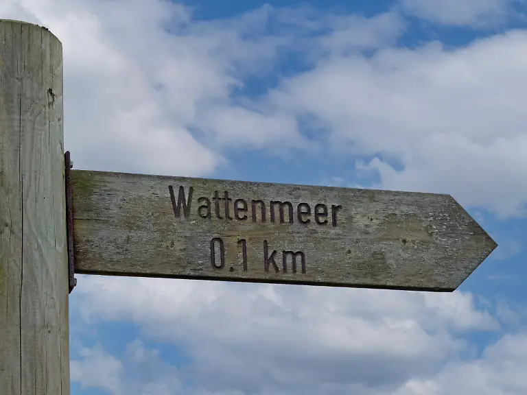 Hoelzernes-Hinweisschild-das-den-Weg-zum-Wattenmeer-weist-im-Nationalpark-Niedersaechsisches-Wattenmeer-Deutschland-Wooden-sign-pointing-the-way-to-the-Wadden-Sea-in-Lower-Saxony-Wadden-Sea-National-Park-Germany