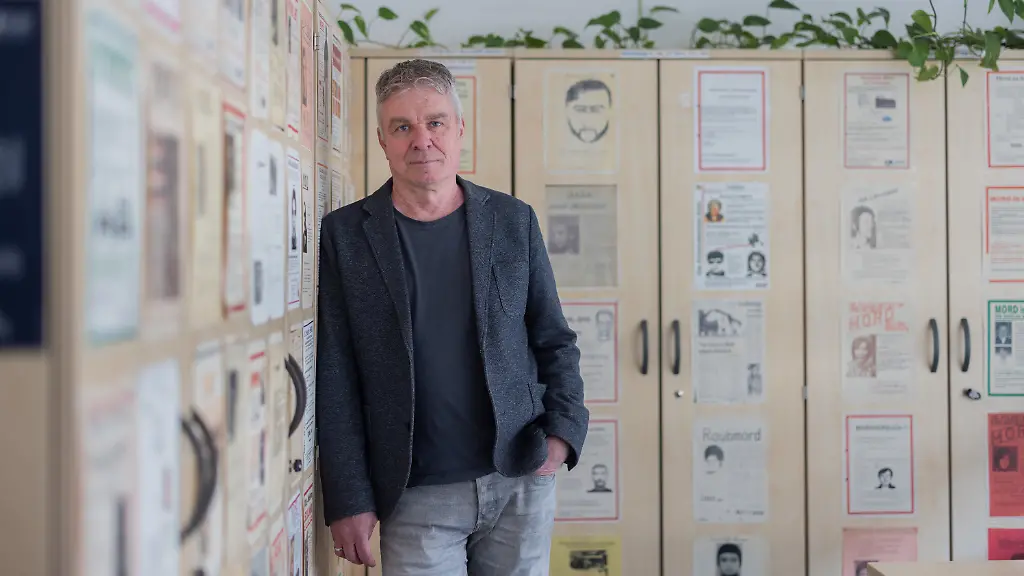 PRODUKTION-25-03-2026-Nordrhein-Westfalen-Koeln-Markus-Weber-Leiter-Ermittlungsgruppe-Cold-Cases-der-Koelner-Polizei-steht-in-einem-Buero-im-Polizeipraesidium-vor-Bueroschraenken-auf-denen-Fahndungsplakate-mit-ungeloesten-Faellen-haengen-Seit-2022-ist-er-Leiter-der-damals-neu-gegruendeten-Abteilung-Cold-Cases-bei-der-Koelner-Polizei-In-Koeln-und-Umgebung-gibt-es-nach-Schaetzung-von-Weber-mehr-als-250-offene-sogenannte-Cold-Cases-jahrzehntelang-zurueckliegende-Verbrechen-die-bis-heute-nicht-geloest-sind