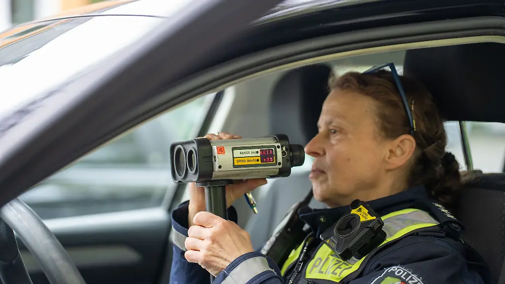Eine-Polizeibeamtin-misst-im-Rahmen-der-sogenannten-Speedweek-auf-einer-Landstrasse-mit-der-Radarpistole-die-Geschwindigkeit-der-Fahrzeuge