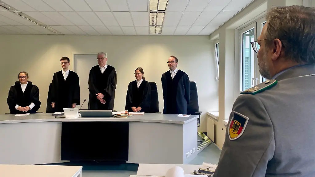 Der-Vorsitzende-Richter-Egbert-Schneider-3-v-l-steht-vor-dem-Prozessvertreter-der-Bundeswehr-r-zu-Beginn-der-Verhandlung-ueber-die-Klage-eines-Soldaten-der-Reserve-gegen-eine-Zurueckstellung-wegen-der-Teilnahme-an-einer-extremistischen-Demonstration-Dem-Klaeger-wurde-vom-Militaer-vorgeworfen-2017-an-einer-Demonstration-der-rechtsextremistischen-Identitaeren-Bewegung-teilgenommen-zu-haben-was-seine-Verfassungstreue-in-Frage-stelle