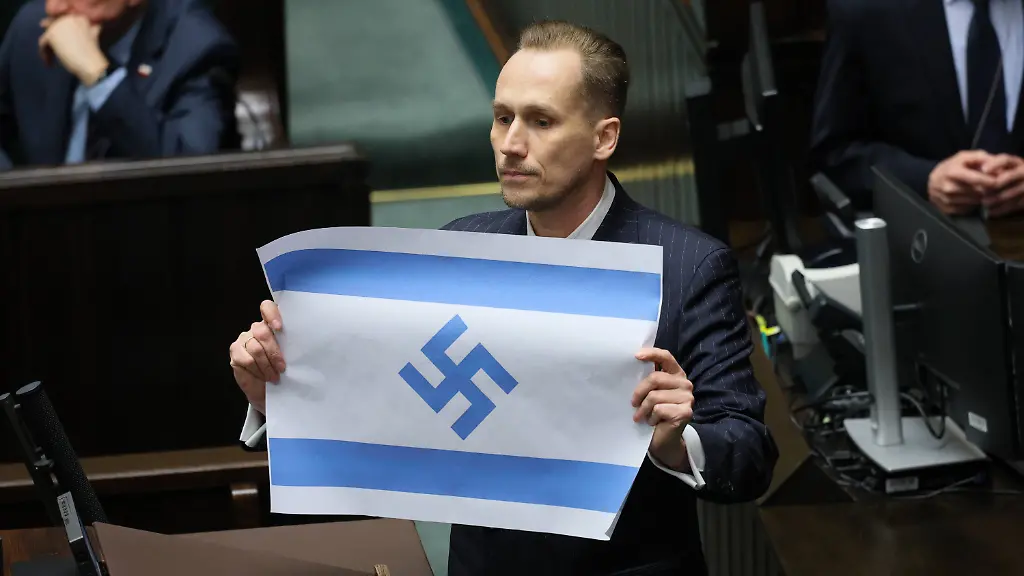 Konrad-Berkowicz-Abgeordneter-im-Sejm-in-Warschau-Polen-haelt-eine-israelische-Flagge-mit-einem-Hakenkreuz