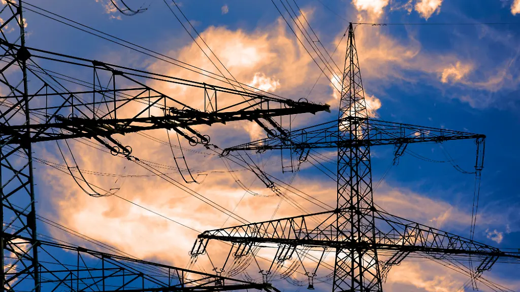 Hochspannungsmasten-stehen-vor-einem-Himmel-mit-dramatischen-Wolken-als-Symbolbild-fuer-die-Infrastruktur-der-Energieversorgung-durch-Elektrizitaet-FOTOMONTAGE