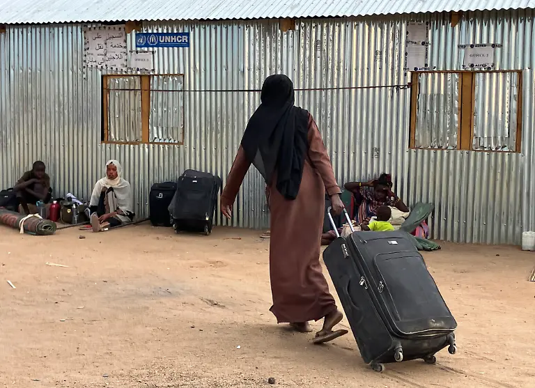 Eine-Frau-aus-dem-Sudan-zieht-ihren-Koffer-durch-das-Transitlager-2-in-der-suedsudanesischen-Grenzstadt-Renk-Urspruenglich-war-das-Lager-fuer-3000-Menschen-geplant-die-nach-zwei-Wochen-zu-ihren-neuen-Bestimmungsorten-weiterreisen-sollten-Der-seit-April-2023-andauernde-blutige-Machtkampf-im-Sudan-hat-die-nach-UN-Angaben-weltweit-groesste-Fluechtlingskrise-ausgeloest-Mehr-als-acht-Millionen-Menschen-sind-innerhalb-des-Sudan-auf-der-Flucht-oder-in-Nachbarlaender-wie-Suedsudan-und-Tschad-geflohen-Auch-das-Transitlager-in-Renk-erhaelt-taeglich-hunderte-von-Neuankoemmlingen-die-nun-oft-laenger-als-urspruenglich-geplant-bleiben-muessen