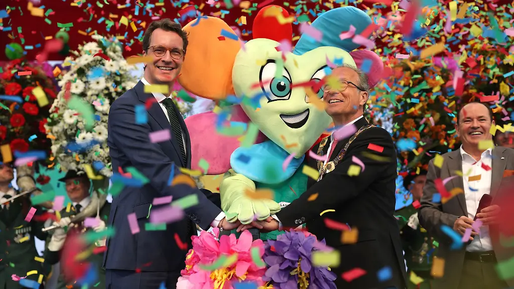 Moderator-Wolfram-Kons-r-steht-neben-Ministerpraesident-Hendrik-Wuest-l-CDU-und-Buergermeister-Reiner-Breuer-m-SPD-auf-der-Buehne-die-die-Landesgartenschau-eroeffnen