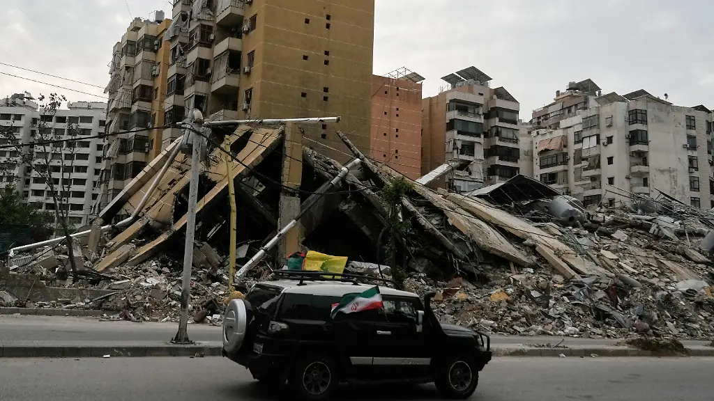 17-04-2026-Libanon-Beirut-Vertriebene-Bewohner-in-einem-Fahrzeug-die-iranische-und-Hisbollah-Fahnen-schwenken-passieren-die-Truemmer-zerstoerter-Gebaeude-in-Dahija-den-suedlichen-Vororten-von-Beirut-nach-dem-Inkrafttreten-einer-Waffenruhe