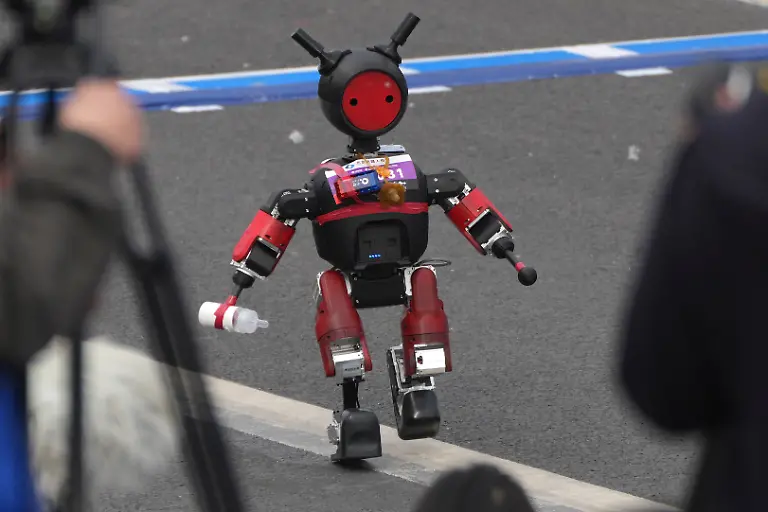 Ein-Roboter-der-einem-Kleinkind-mit-einer-Milchflasche-aehnelt-startet-beim-Beijing-E-Town-Half-Marathon-und-Humanoid-Half-Marathon-am-Stadtrand-von-Beijing
