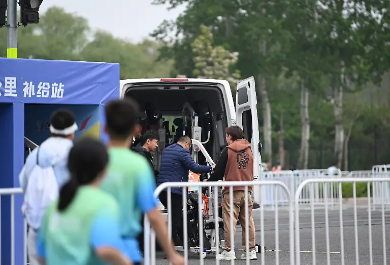 An-einer-Station-bei-Kilometer-16-tauschen-Mitarbeiter-einen-humanoiden-Roboter-aus-In-Peking-sind-humanoide-Roboter-bei-einem-Halbmarathon-gegen-Menschen-angetreten