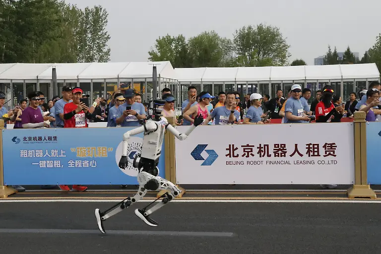 Humanoid-robots-break-half-marathon-world-record-in-China-BEIJING-CHINA-APRIL-19-A-humanoid-robot-runs-alongside-participants-during-a-long-distance-race-breaking-the-half-marathon-world-record-by-surpassing-human-performance-potential-in-Beijing-China-on-April-19-2026-Emre-Aytekin-Anadolu-Beijing-China-Editorial-use-only-Please-get-in-touch-for-any-other-usage