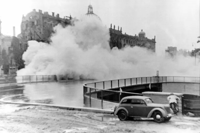 Das-Schwarz-Weiss-Archivbild-vom-07-09-1950-zeigt-wie-der-so-genannte-Apotheken-Fluegel-der-aelteste-Teil-des-Berliner-Stadtschlosses-gesprengt-wird-Von-dem-Schloss-standen-nur-noch-einige-Reste-Es-war-im-Zweiten-Weltkrieg-schwer-beschaedigt-worden-Mit-dem-Sprengen-der-Ruine-und-dem-voelligen-Abtragen-der-Ueberbleibsel-wollte-der-damalige-SED-Chef-Walter-Ulbricht-ein-Zeichen-setzen-dass-es-mit-der-Herrschaft-von-Kurfuersten-Koenigen-und-Kaisern-endgueltig-vorbei-sei-Mehr-als-zwei-Jahrzehnte-spaeter-sollte-an-dieser-Stelle-ein-neuer-Prunkbau-entstehen-der-Palast-der-Republik-dpa-lbn-zu-dpa-Reportage-Wenn-Geschichte-persoenlich-wird-Streit-um-den-Palast-der-Republik-vom-17-04