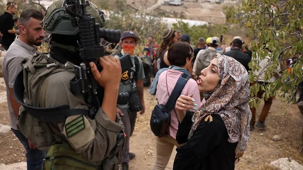 A-Palestinian-woman-speaks-to-an-Israeli-soldier-in-the-village-of-Edna-north-of-the-occupied-West-Bank-city-of-Hebron-during-the-olive-harvesting-season-on-October-12-2025
