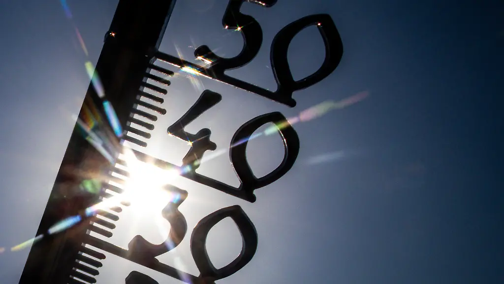 Vor-einem-wolkenlosen-blauen-Himmel-zeigt-ein-Aussenthermometer-in-einem-Garten-bereits-am-Vormittag-ueber-30-Grad-Lufttemperatur-an