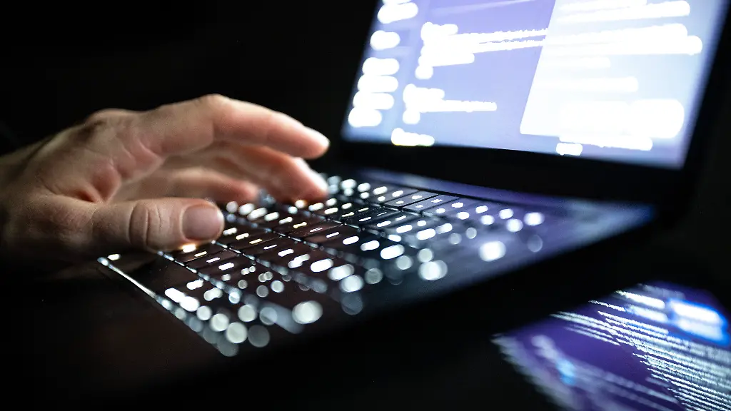 Eine-Person-tippt-mit-den-Fingern-auf-einer-beleuchteten-Laptop-Tastatur