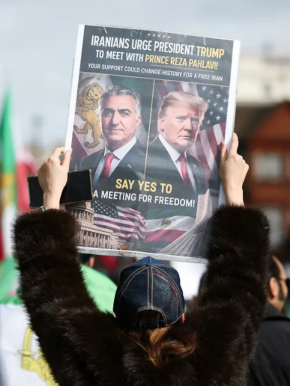 A-person-holds-a-sign-featuring-images-of-Reza-Pahlavi-the-exiled-son-of-Iran-s-last-shah-and-an-Iranian-opposition-figure-and-U-S-President-Donald-Trump-during-a-protest-against-the-Iranian-government-amid-the-U-S-Israel-conflict-with-Iran-in-London-Britain-April-4-2026