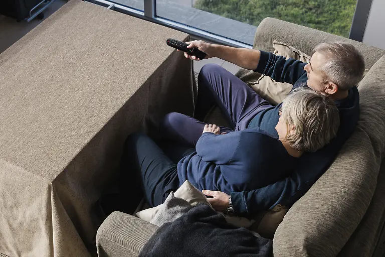 Ein-aelteres-Ehepaar-sitzt-eng-auf-einer-bequemen-Couch-und-verbringt-einen-friedlichen-Moment-vor-dem-Fernseher